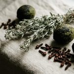 Green black walnut hulls, a bundle of dried wormwood and whole clove buds arranged on linen